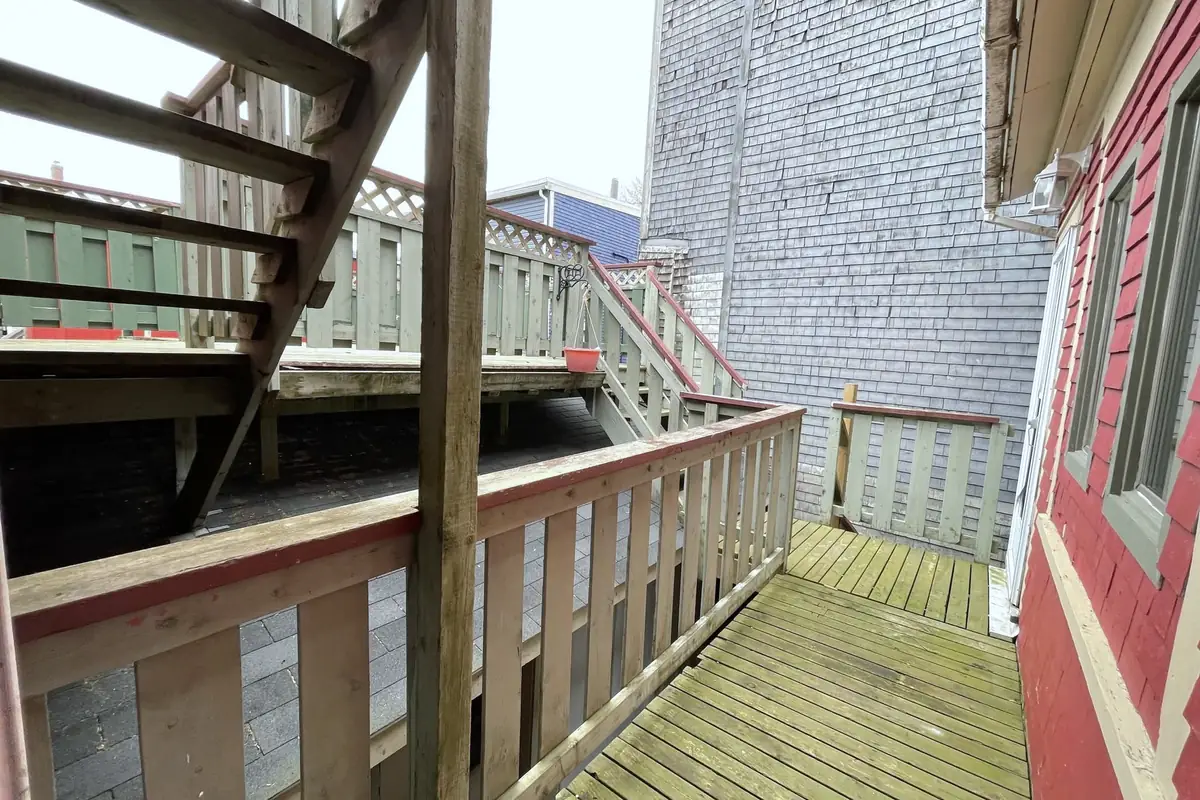 Wooden back decks with railings and stairs between two houses.