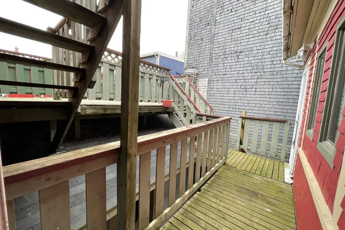 Wooden back decks with railings and stairs between two houses.